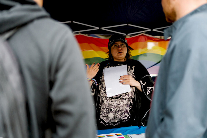 Menschen im Gespräch im Hintergrund eine Regenbogenflagge