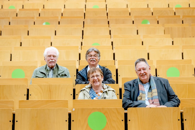 Eine Gruppe von vier ehemaligen Studierenden sitzen im Hörsaal