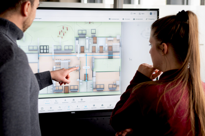 Zwei Personen vor einem Bildschirm mit einem Gebäudemodell