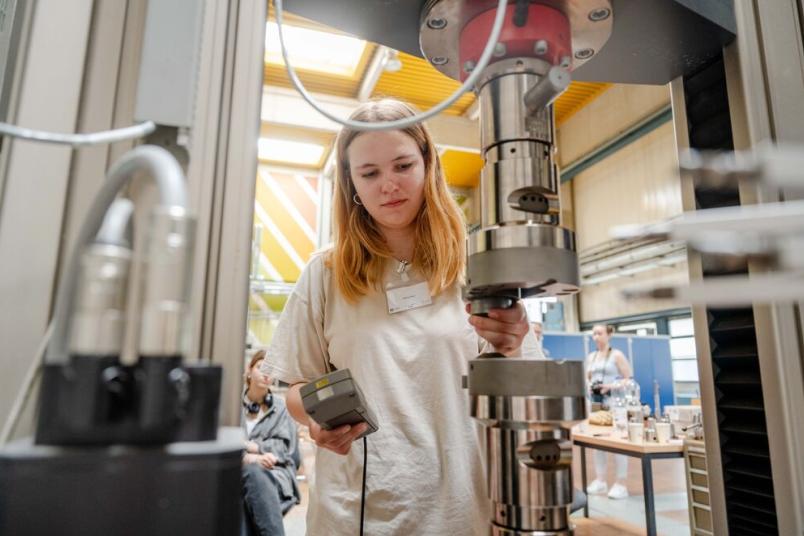 Eine Person setzt eine Metallprobe in einen Versuchsstand ein.