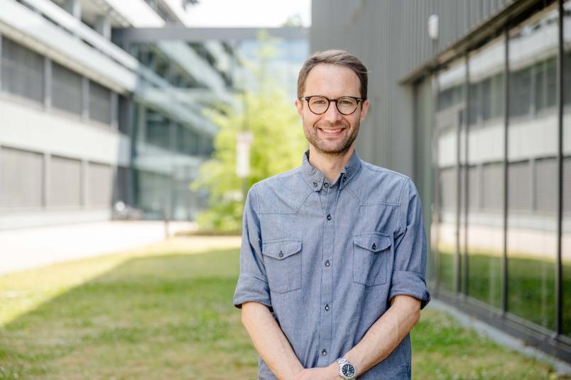 Eine Person in blauem Hemd vor einem Gebäude
