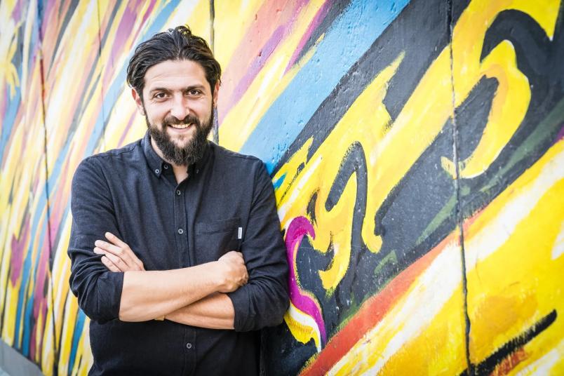 El Mafaalani steht vor eine bunten Wand.