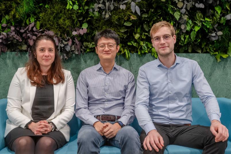 Célia Millon, Yicheng Wang und Michael Müller sitzen auf einer Bank im Foyer des Gebäudes UV.