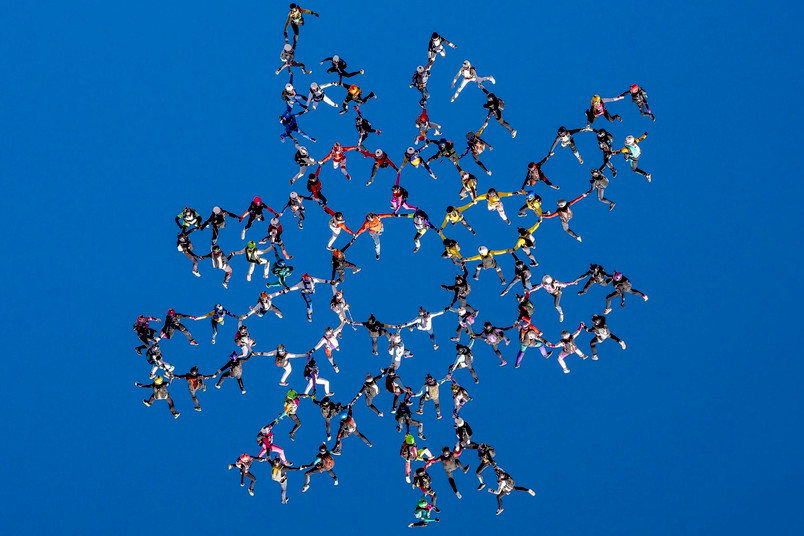 Eine große Zahl Fallschirmspringerinnen bilden während des freien Falls eine wabenförmige Formation.
