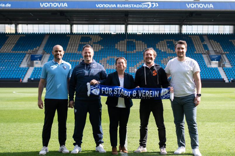 Gruppenbild im Stadion mit 5 Personen, die gemeinsam einen VfL-Bochum-Schal zeigen