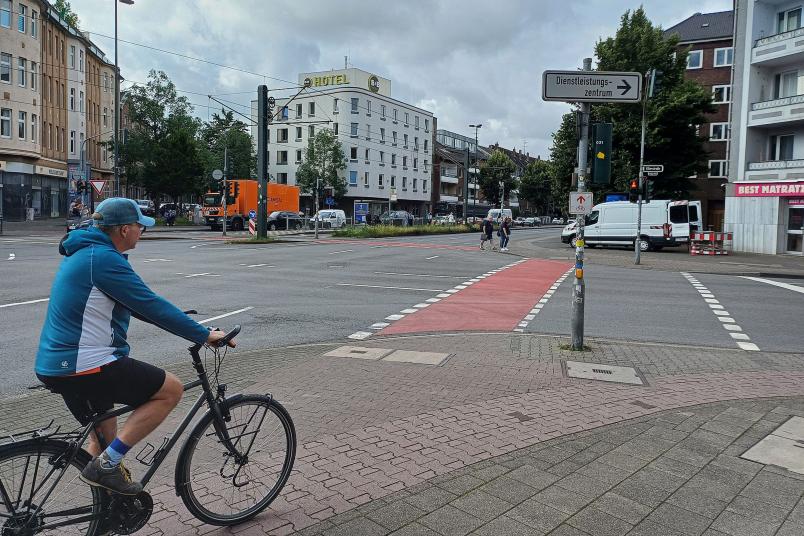 Radfahrer fährt auf eine rote Radfuhrt zu
