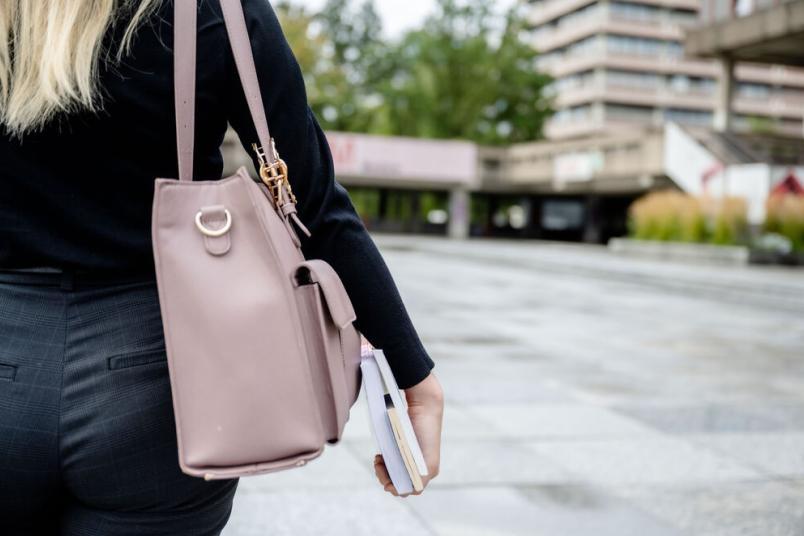 Studentin trägt Tasche und Bücher. 