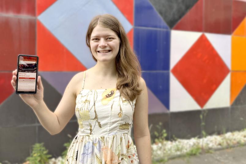 Studentin hält Handy hoch. 
