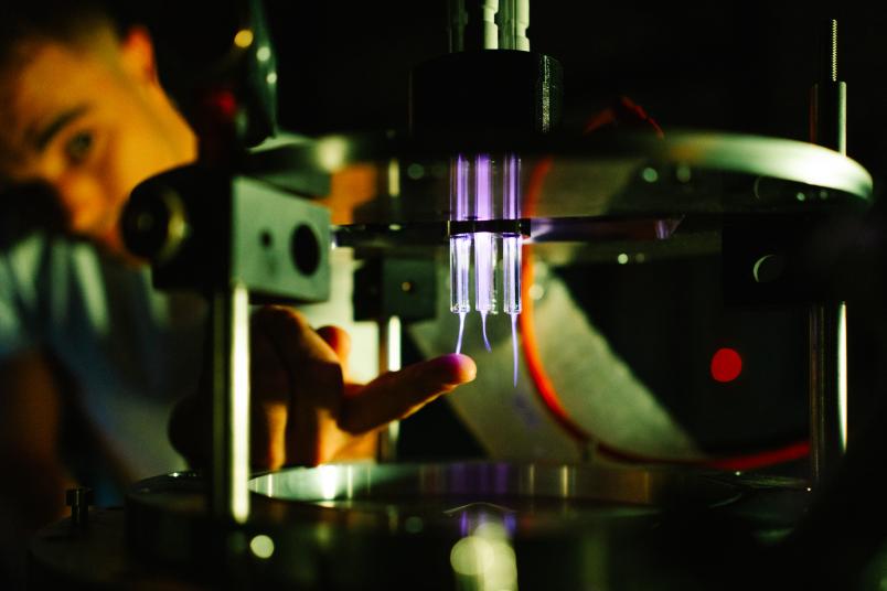 Eine Person fasst in eine Apparatur, in der es violett leuchtet