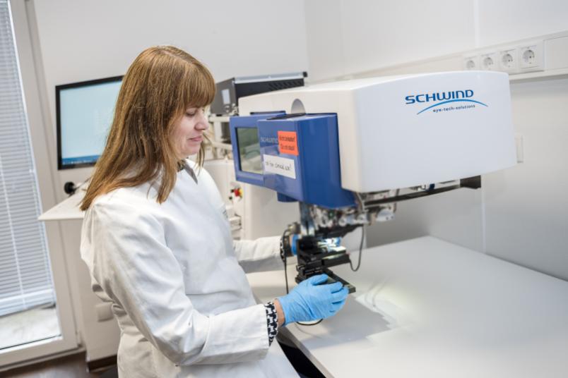 Eine Frau im weißen Kittel bedient ein Lasergerät