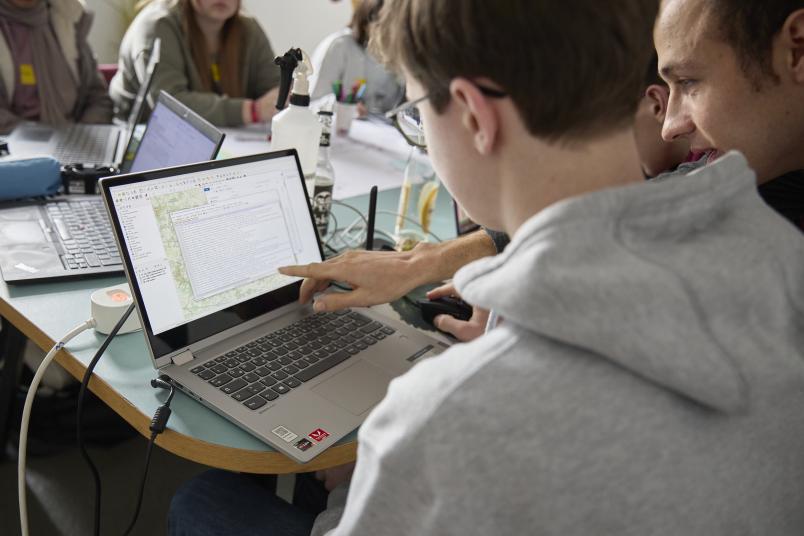Zwei junge Männer schauen auf einen Laptopbildschirm