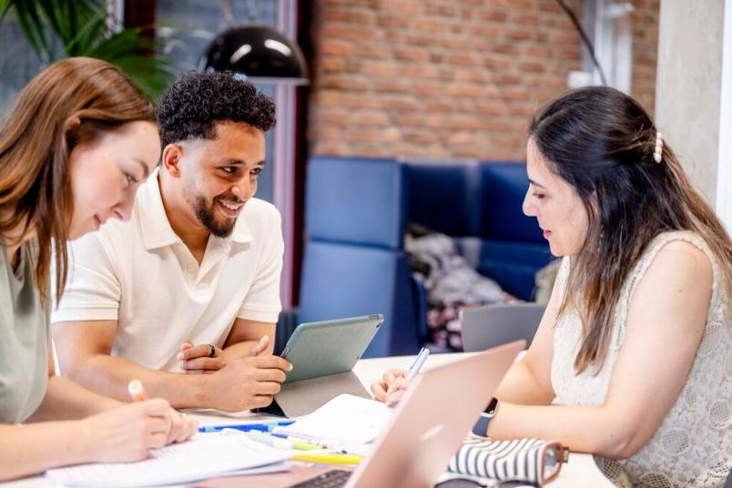 Drei Studierende sitzen in der Bibliothek