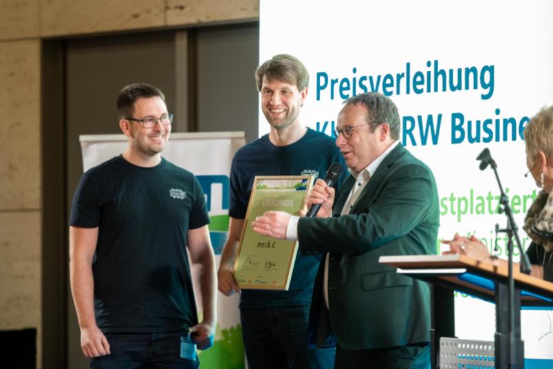 Preisverleihung, drei Männer stehen auf einer Bühne