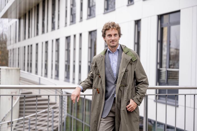 Ein Mann im Mantel lehnt an einem Geländer