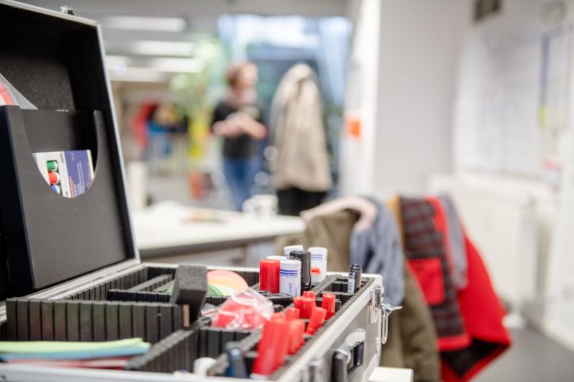 Workshop-Impression mit Moderationskoffer im Vordergrund und Personen im Hintergrund