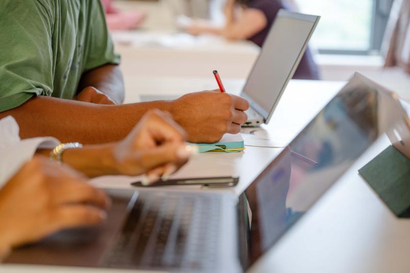 man sieht Hände und Arme und zwei aufgeklappte Laptops