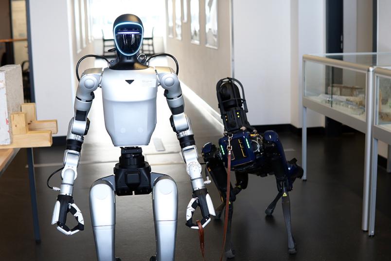 Ein humanoider Roboter hält einen hundeartigen Roboter an der Leine