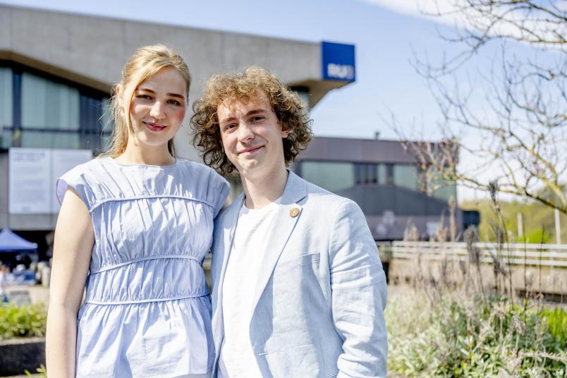 Studentin und Student vor frühlingshafter Kulisse