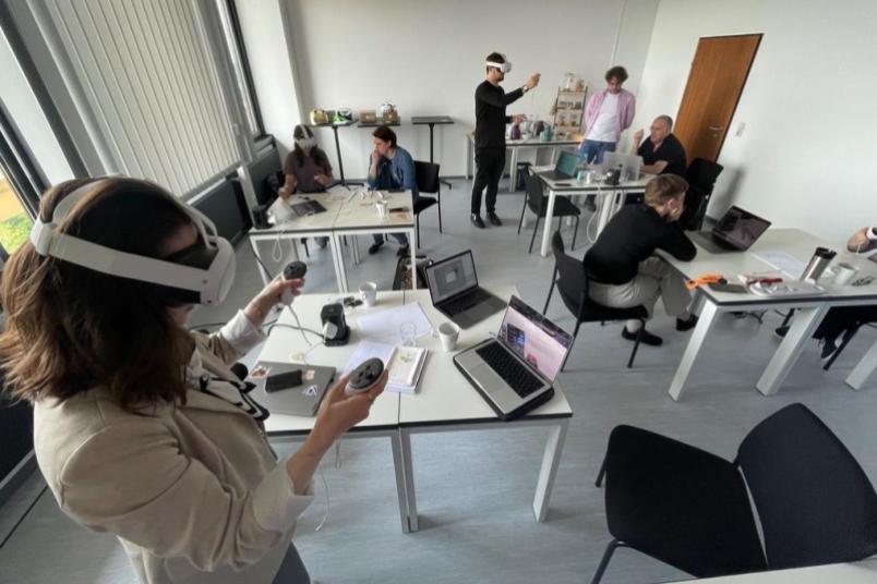 Eine Frau mit VR-Brille in einem Seminarraum mit weiteren Menschen