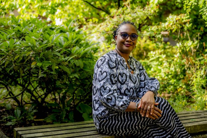Porträt einer afrikanischen Gastwissenschaftlerin sitzend im Grünen.