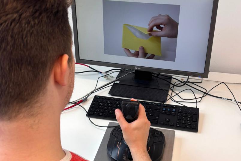 Blick über die Schulter eines Mannes, der mit Joystick am Computerbildschirm sitzt