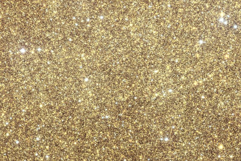 Ein sehr dichtes Feld aus winzigen, eng beieinander liegenden Lichtpunkten füllt das Bild. Die Farbe ist fast einheitlich und wird von leuchtenden Gelb- und Goldtönen dominiert. Kleine weiße Punkte erscheinen hier und da etwas heller, mit einigen blassen bläulichen Punkten dazwischen verstreut. 