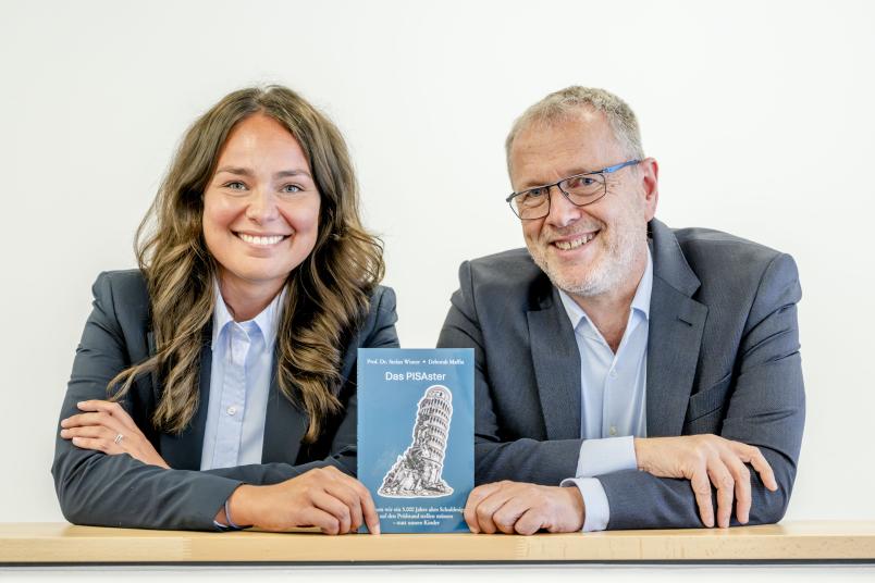Porträt von Deborah Maffia und Stefan Winter mit dem Buch "Das PISAster"