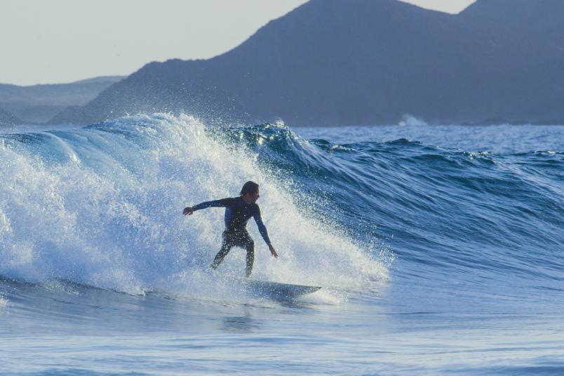 Surfer im Wasser vor einer Welle