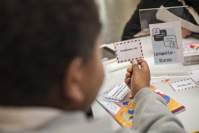 Ein Kind hält eine laminierte Karte mit der Aufschrift ""Briefkasten, der"