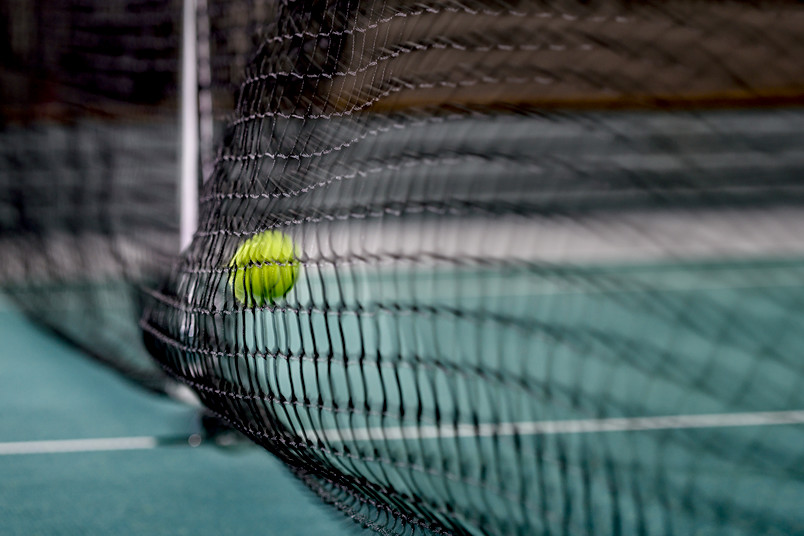 Ein Tennisball fliegt ins Netz.