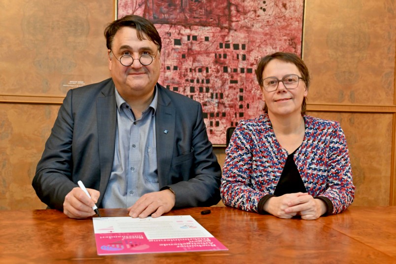 Rektor Martin Paul und Kanzlerin Christina Reinhardt sitzen an einem Tisch und unterzeichnen die Charta für die Ruhr-Universität Bochum.