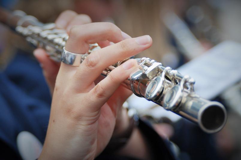Nahaufnahme einer Frau, die Querflöte spielt. Zu sehen sind ihre Hand und das Instrument.