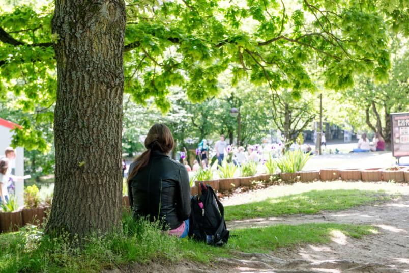 Studentin sitzt auf einer Wiese.