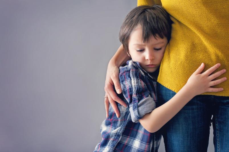 Ein Kind drückt sich ängstlich an seine Mutter