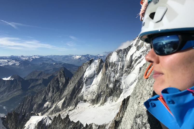 Bergsteigerin blickt von einem Berg ins Tal.