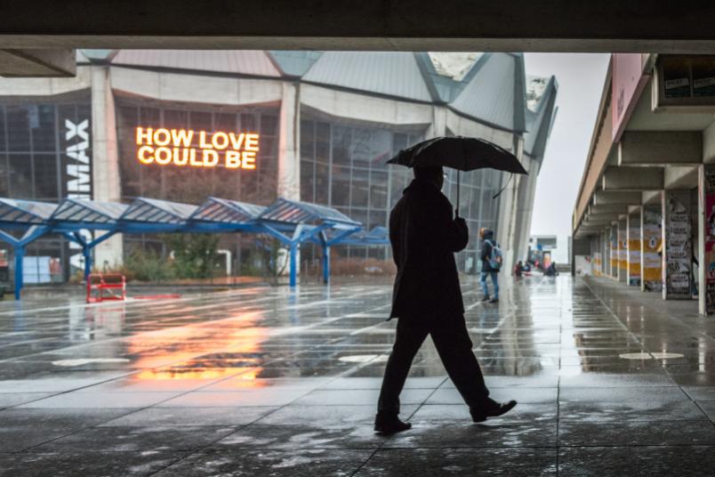 Mann läuft mit Regenschirm über den RUB-Campus.