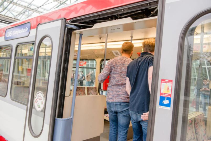 Studierende steigen in die Bahn ein.