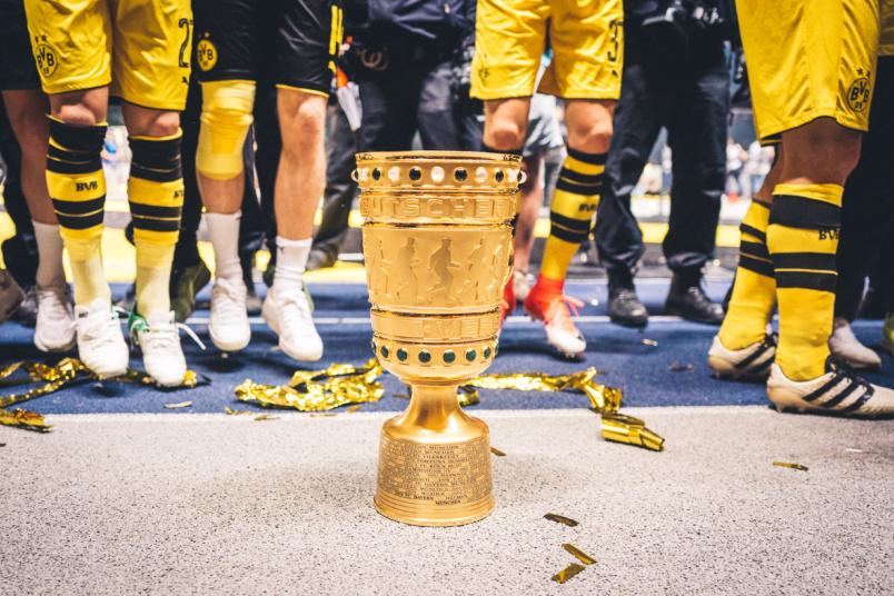 Der DFB-Pokal beim Finalspiel in Berlin – im Hintergrund Beine der Spieler von Borussia Dortmund
