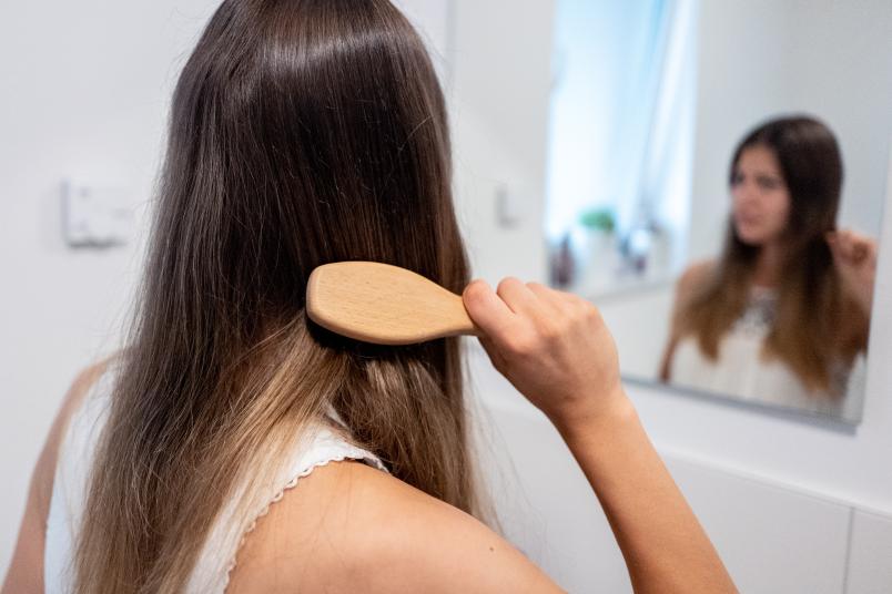 Frau von hinten, die sich die Haare kämmt