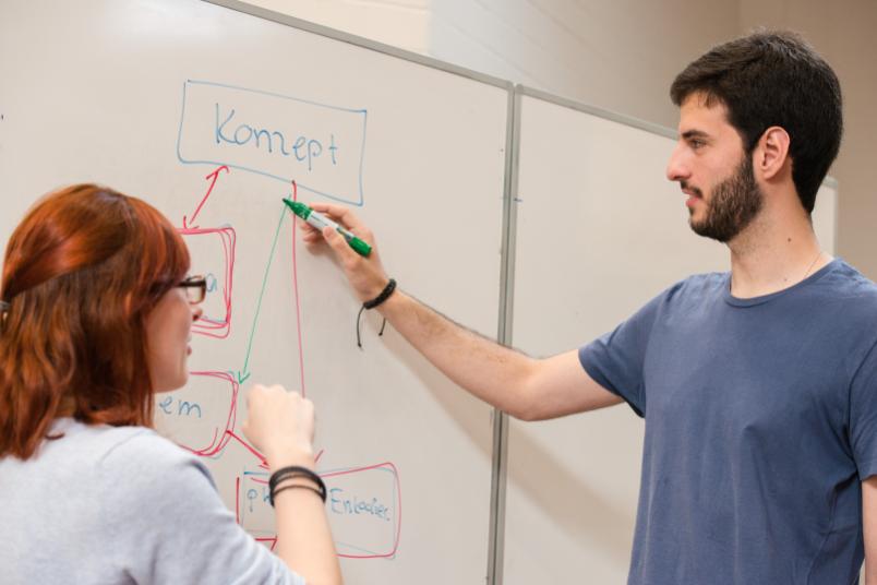Dozentin und Student am Flipchart im Seminarraum