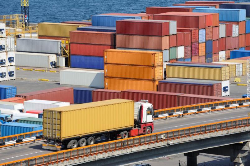 Container im Hafen, davor ein LKW auf der Straße