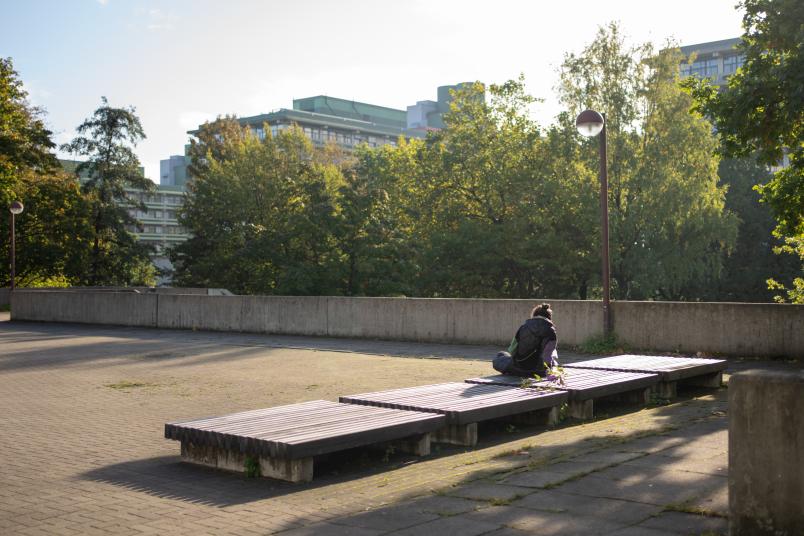 Eine Person sitzt alleine auf dem RUB-Campus.