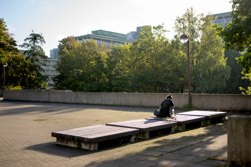 Eine Person sitzt alleine auf dem RUB-Campus.