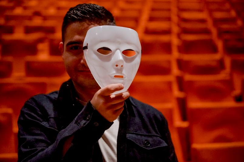 Mann hält eine Theatermaske.