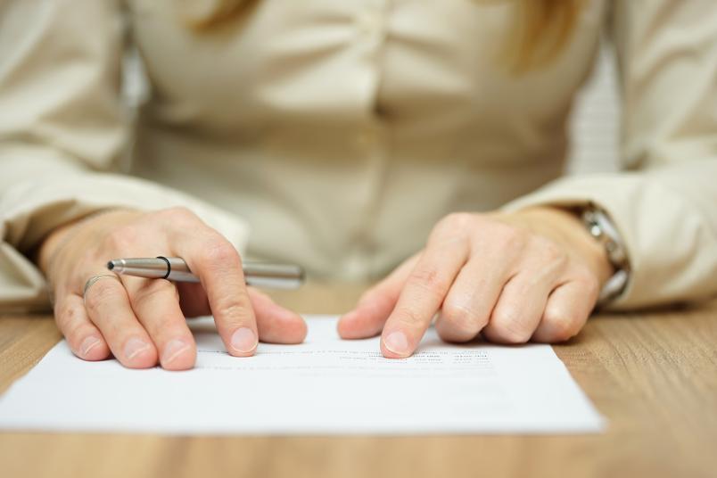 Situation in einer Sitzung: Frau mit Papier und Kugelschreiber in den Händen