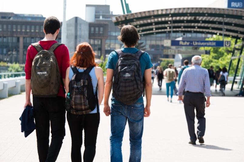 Rückenansicht von drei Studenten auf dem Weg zur RUB.