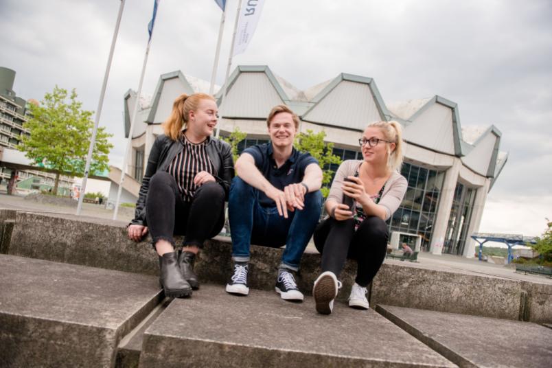 Studierende sitzen vor dem Audimax. 