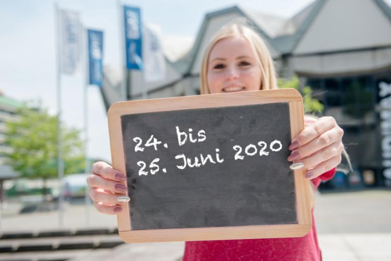 Studentin hält eine kleine Tafel hoch. 