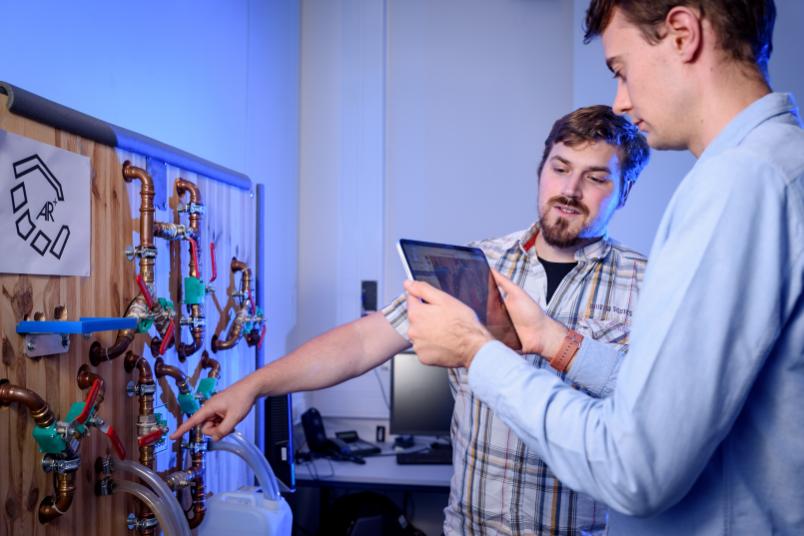 Forscher mit Tablet vor hydraulischem Versuchsstand