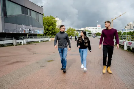 Drei Studierende laufen über den Campus.